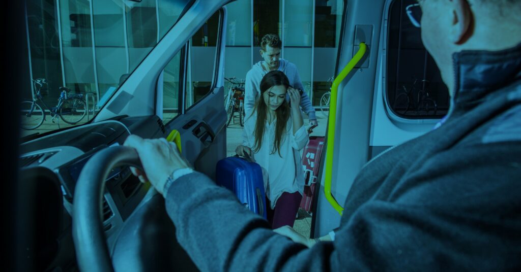 A women followed by a man entering a shuttle Van with their luggage