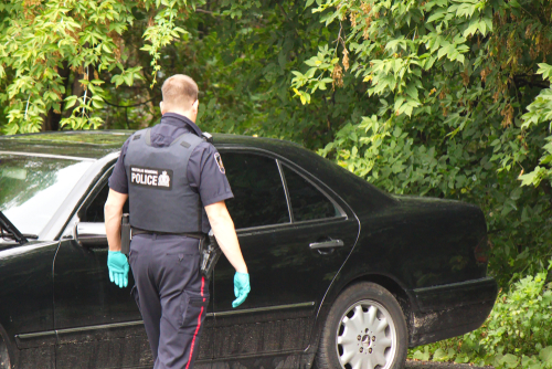 A police officer examines a stolen car.