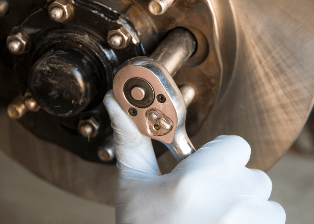 Mechanic turning wrench while installing new brakes