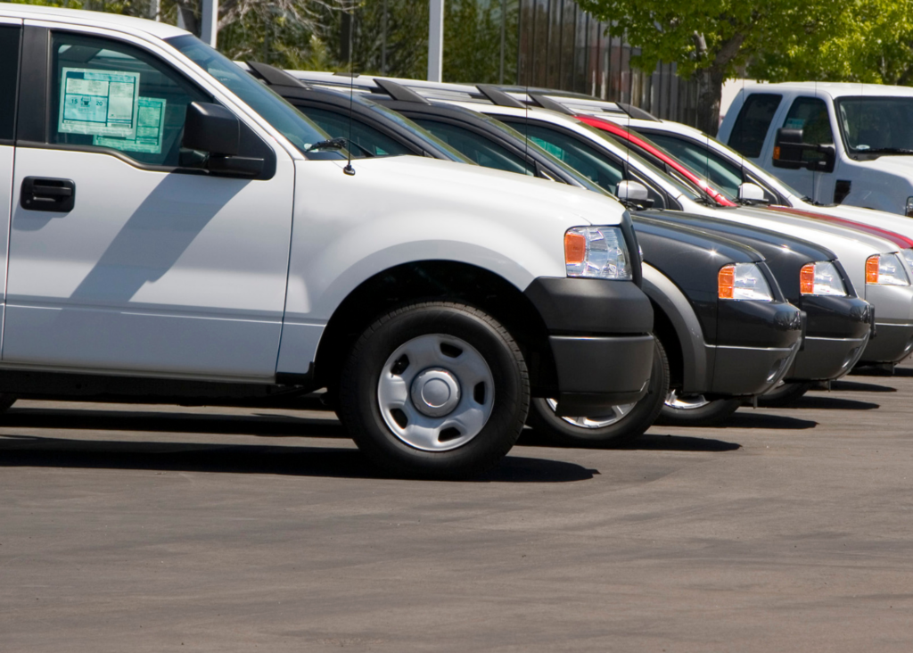 car dealership lot with white pickup truck in foreground