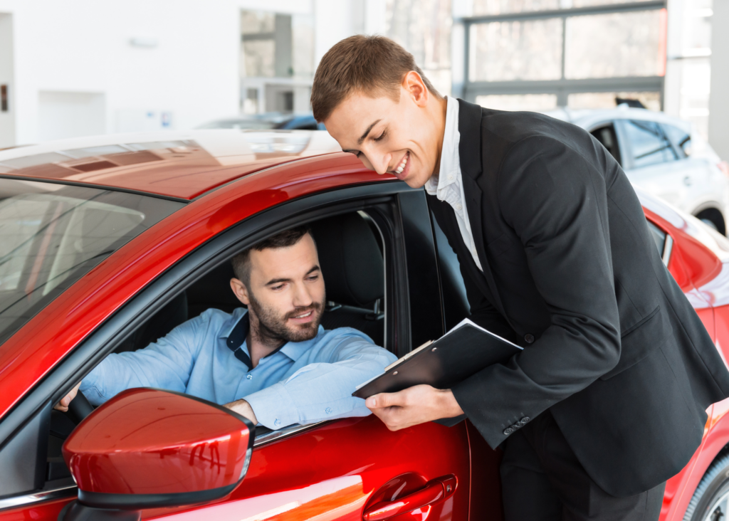 man holding tablet showing mobility data to other man sitting in red car
