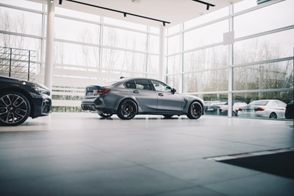 Silver BMW in a dealership showroom surrounded by windows