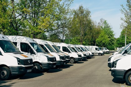 lines of white commercial vans in a vehicle parking lot