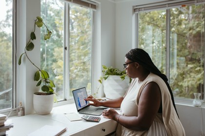 woman with glasses in a home office touching the screen of her laptop computer