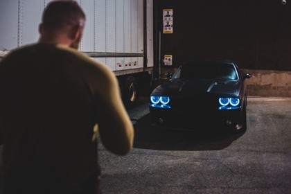 man approaching car next to a truck at night