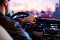 Close up of a man in a car in the driver's seat wearing a nice suit and watch.